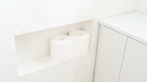 白い壁のトイレ 収納スペースにトイレットペーパーが置かれている