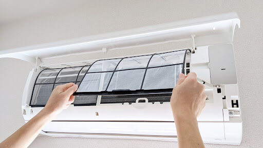 エアコンの本体カバーを開けてフィルターを取り外している