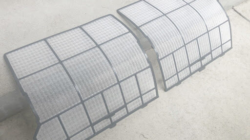 エアコンからフィルターを外して掃除している