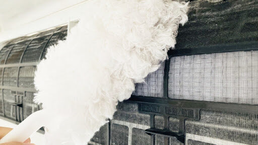 エアコンのカバーを開けてフィルターをハンディモップで掃除している